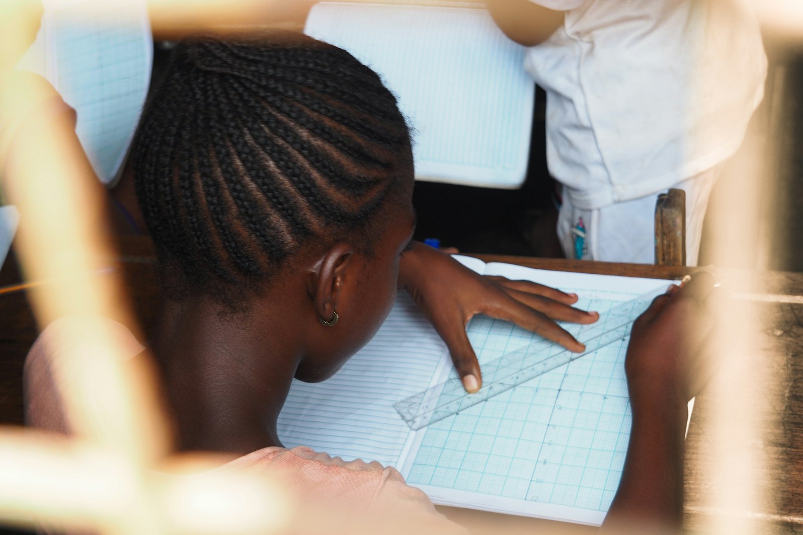 A student carefully drawing lines with a ruler in an exercise book